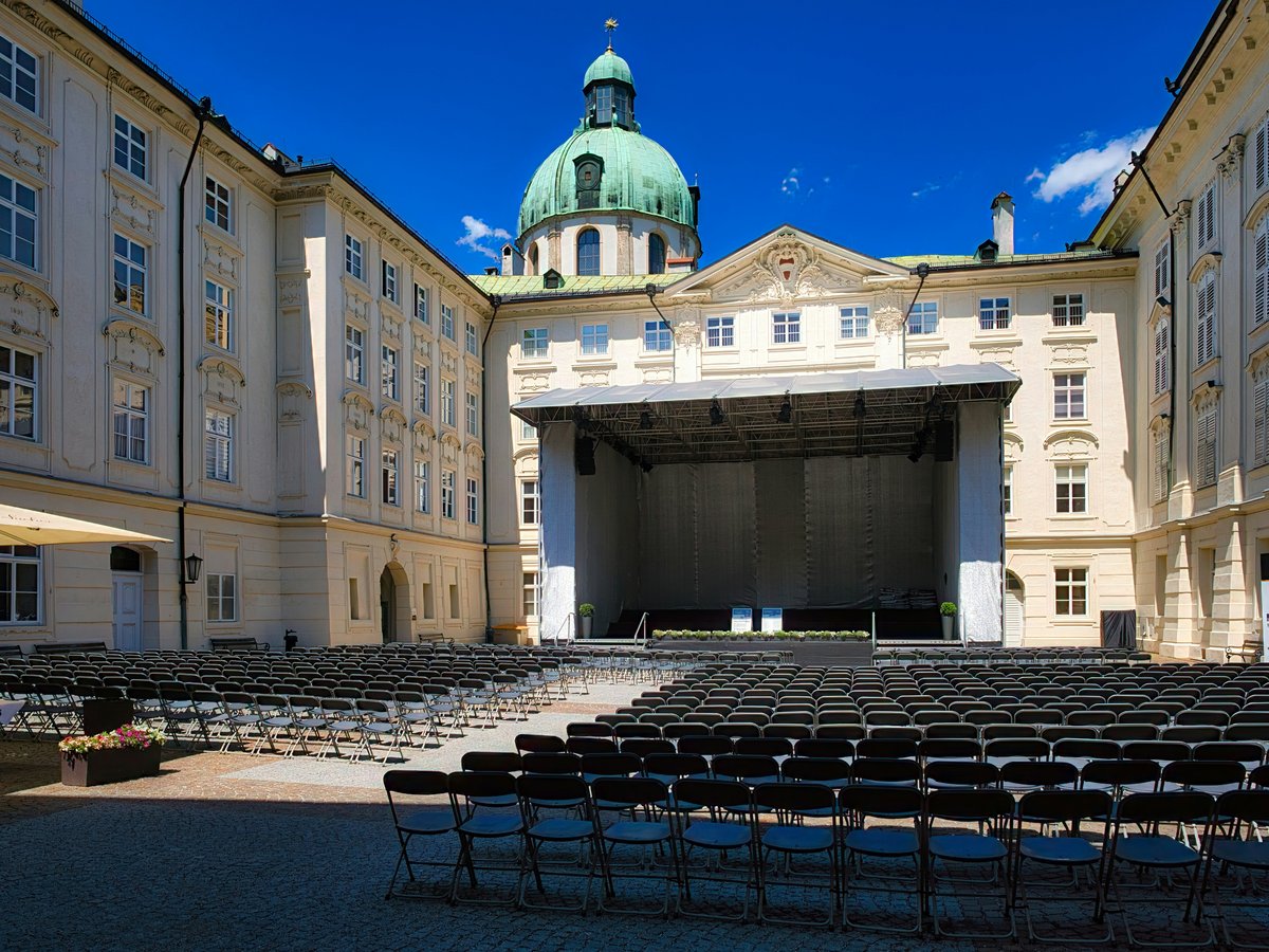 Historic palace courtyard with an outdoor stage and empty seating.