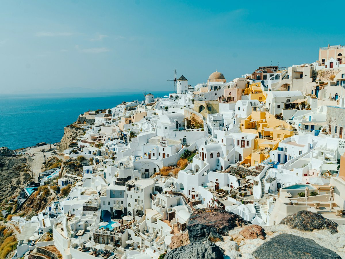 an aerial view of a village on a cliff overlooking the ocean