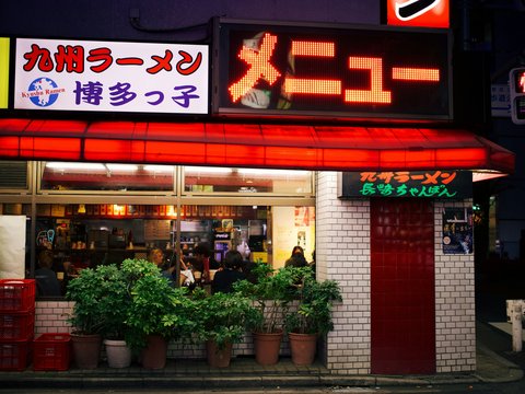 a restaurant with a neon sign above it's entrance