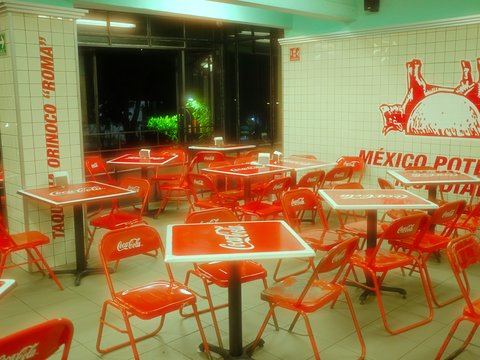 Empty restaurant interior with red tables and chairs at night
