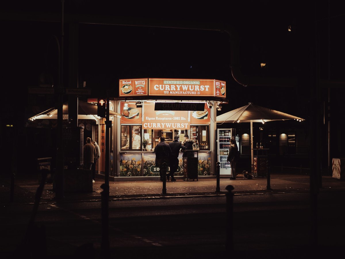 a couple of people standing outside of a store at night
