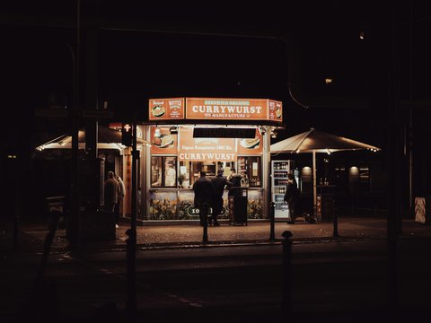 a couple of people standing outside of a store at night