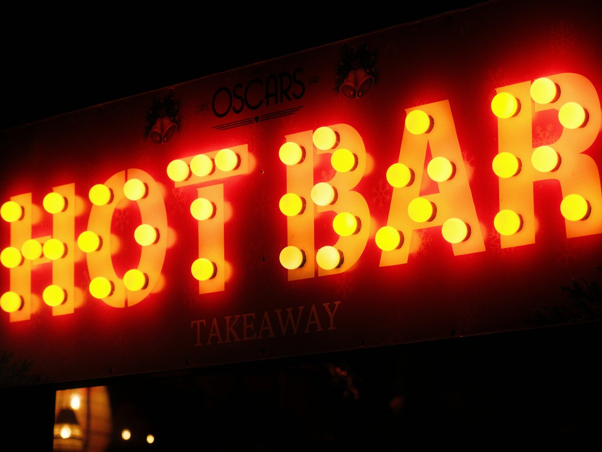Neon sign for "hot bar takeaway" at night