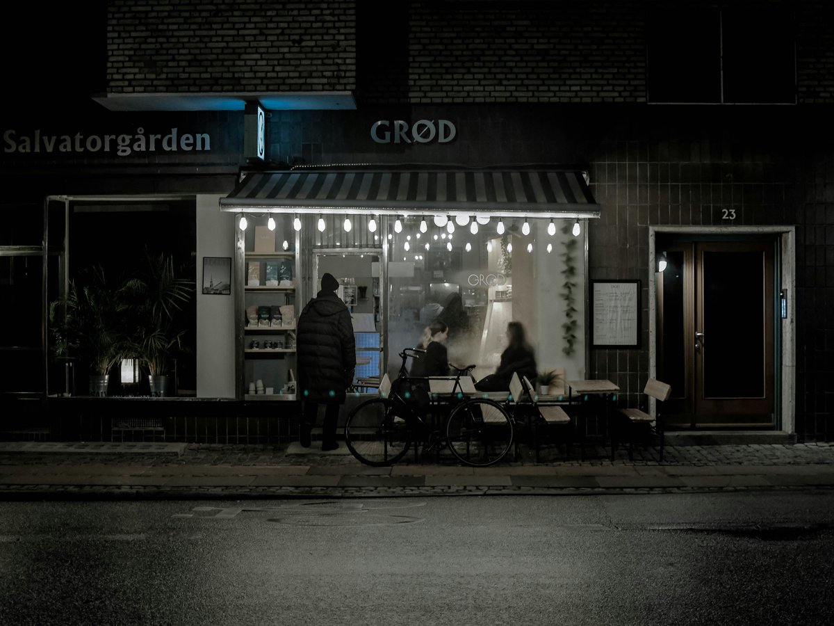 A couple of people standing outside of a store at night