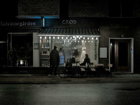 A couple of people standing outside of a store at night