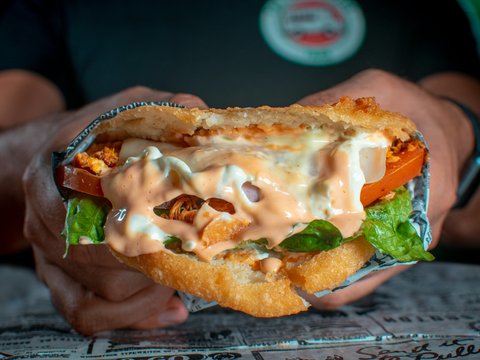 a person holding a sandwich in their hand