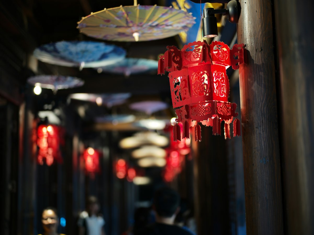 Red lanterns and umbrellas hang in a hallway
