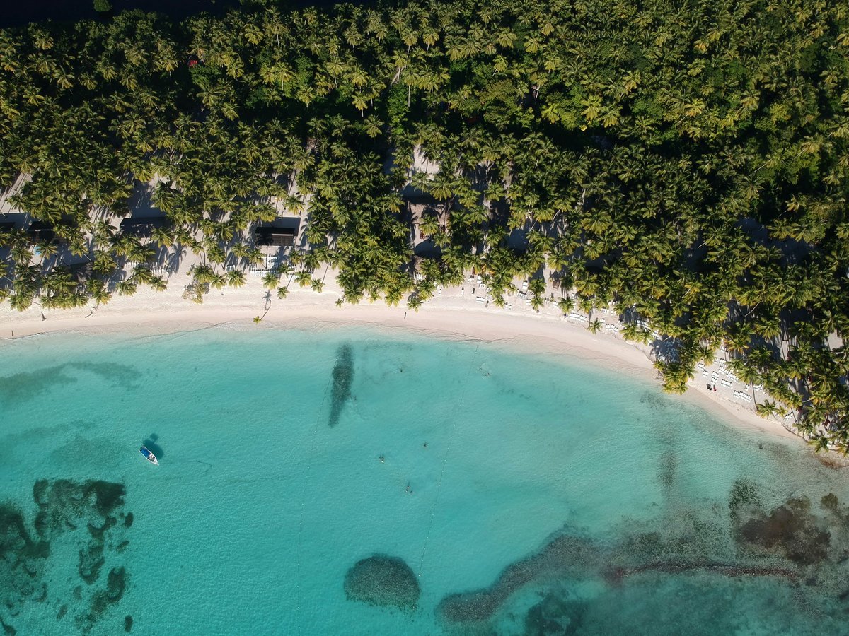 an aerial view of a beach with a boat in the water