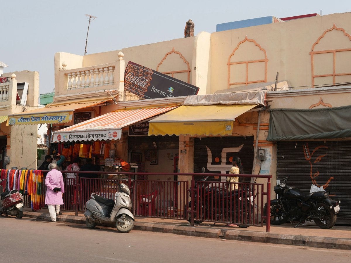Traditional indian shops line a street with parked scooters