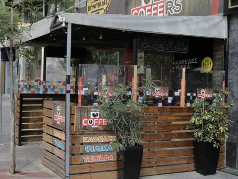 a coffee shop with plants in front of it