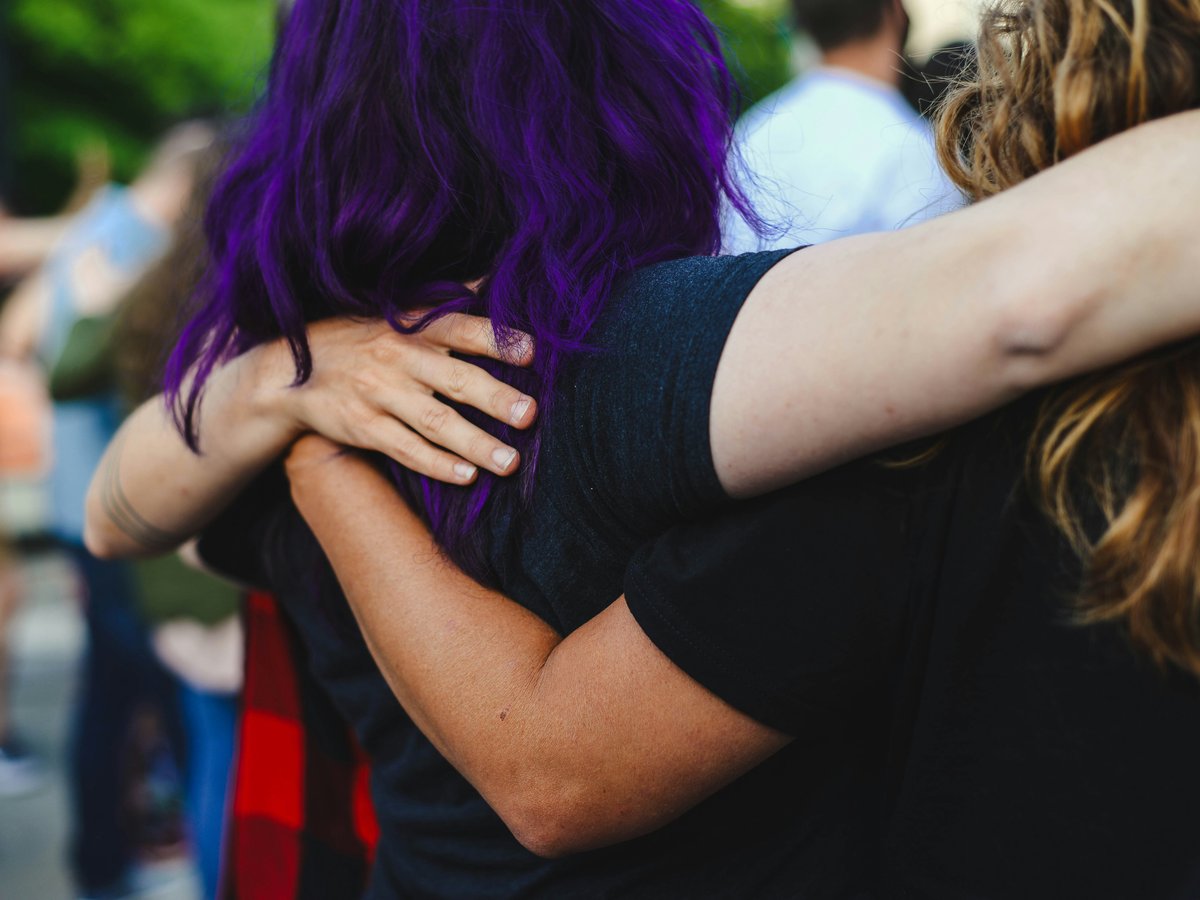 woman in black t-shirt covering face with purple hair
