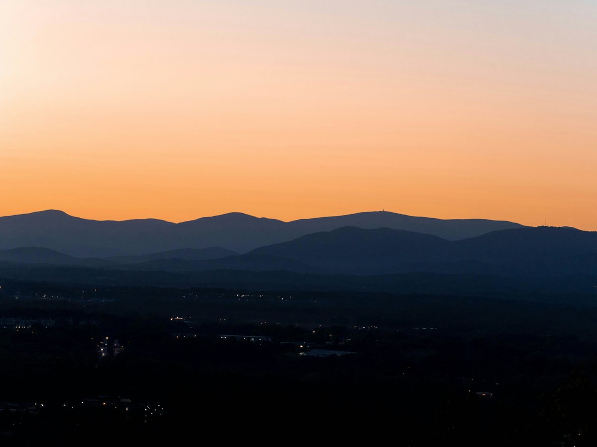 the sun is setting over the mountains in the distance