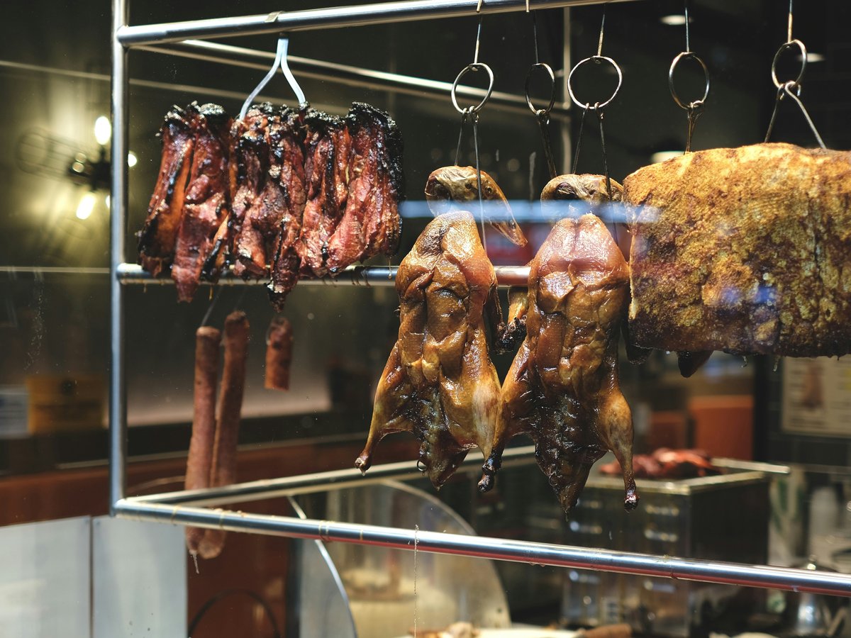 a bunch of meat hanging from hooks in a kitchen