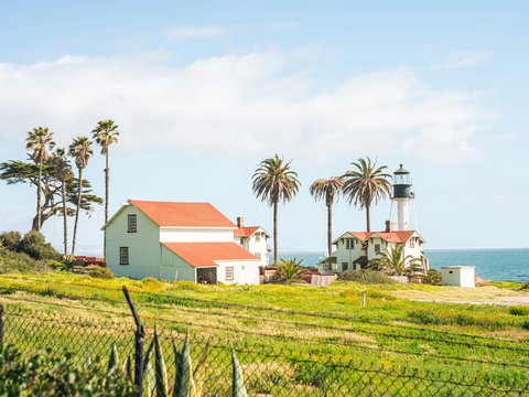 a white house with a red roof next to the ocean