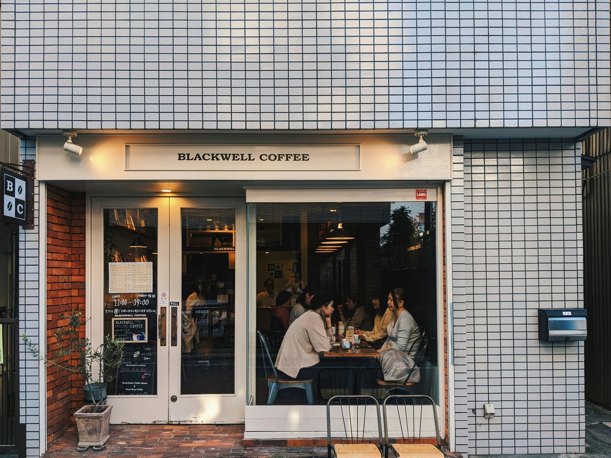 a group of people sitting at a table outside of a coffee shop