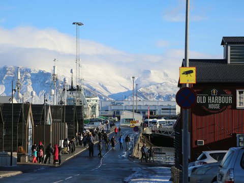 a group of people walking down a street next to a mountain