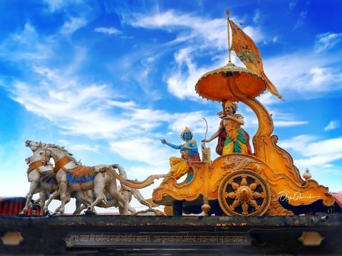 A statue of Krishna and Arjuna on a golden chariot pulled by horses