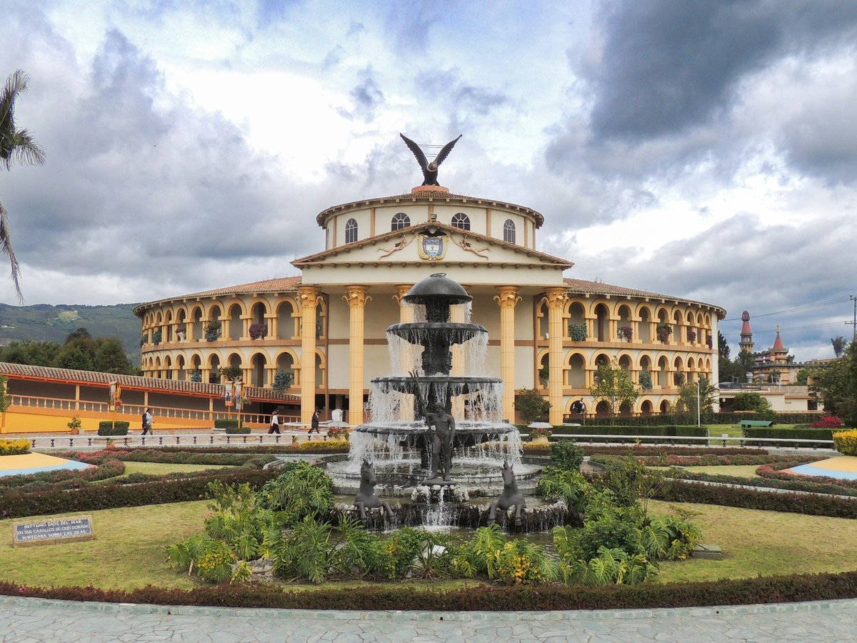 A grand building with a fountain and a cloudy sky.