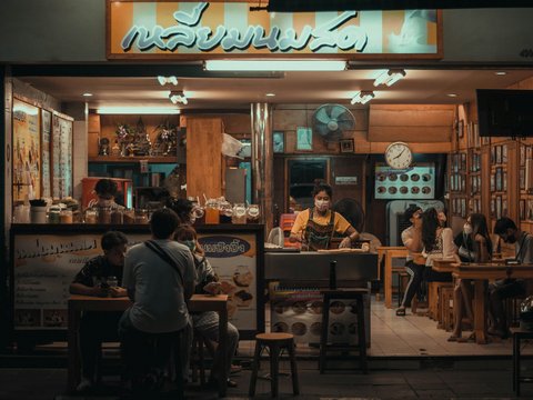 a group of people sitting at a table in front of a restaurant