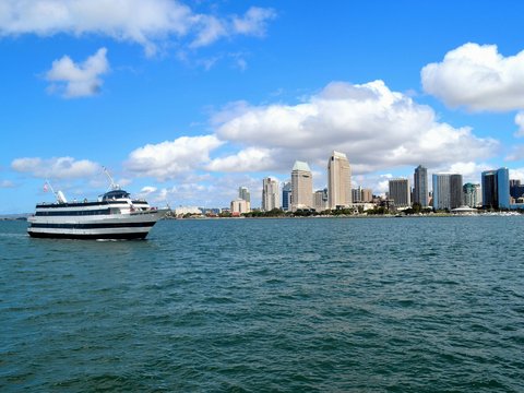 white and black boat on sea near city buildings under blue and white sunny cloudy sky