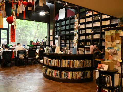 People reading in a cozy bookstore with shelves of books.