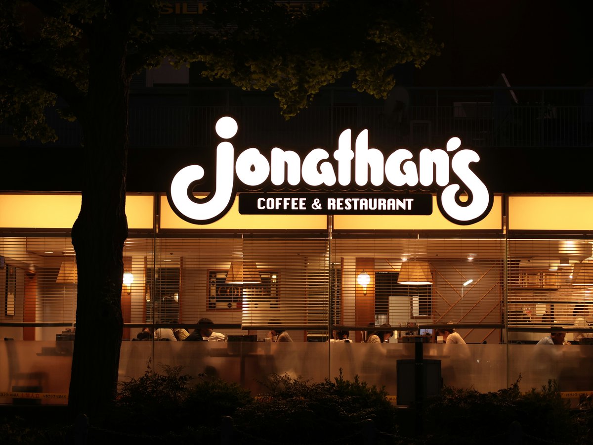 A Jonathan's Coffee & Restaurant sign glowing above a windowed storefront at night