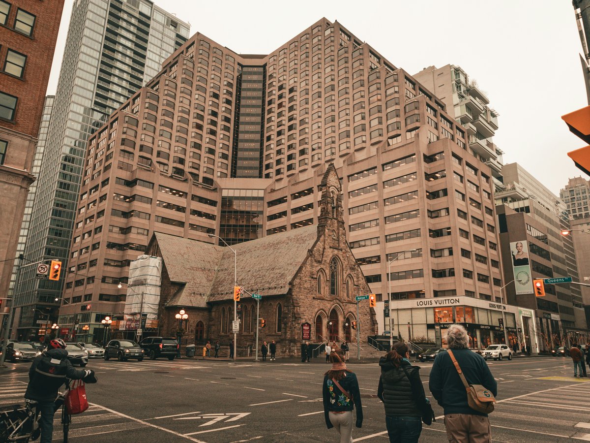 a group of people walking across a street next to tall buildings