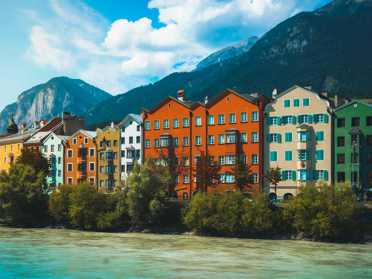 a body of water with buildings along it and mountains in the background