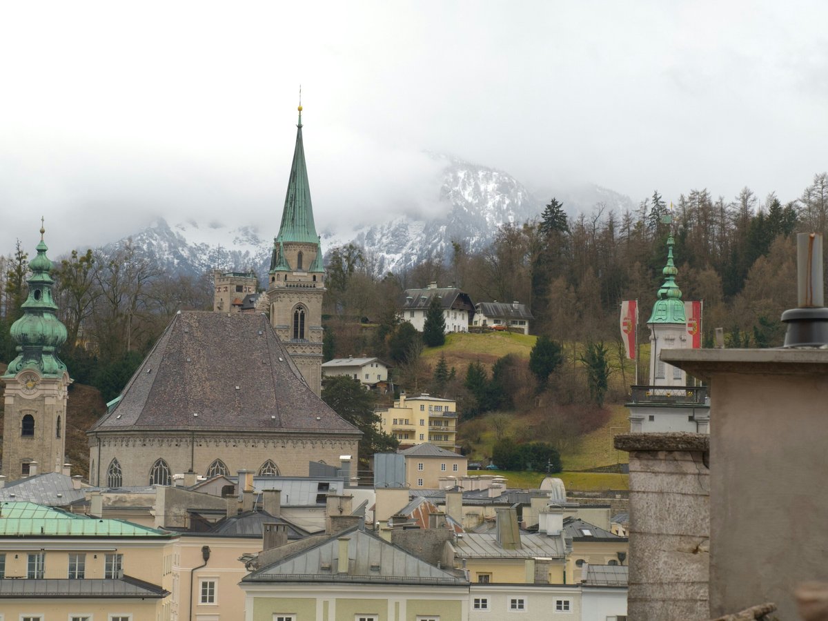Historic european city skyline with church spires and mountains.