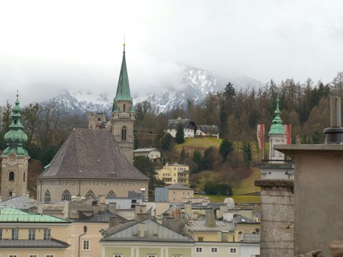 Historic european city skyline with church spires and mountains.