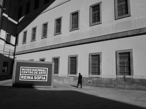 man in black jacket walking on sidewalk near white building during daytime