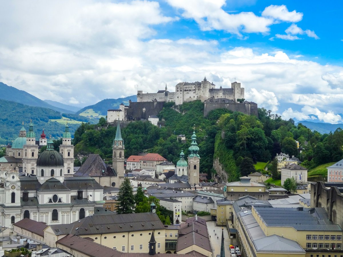Hohensalzburg fortress overlooks salzburg city with mountains.