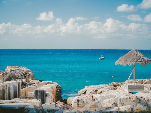 thatch parasol near ruins on island and sea at the distance during day