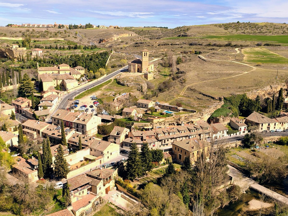 Historic european town with a church tower amidst dry hills.