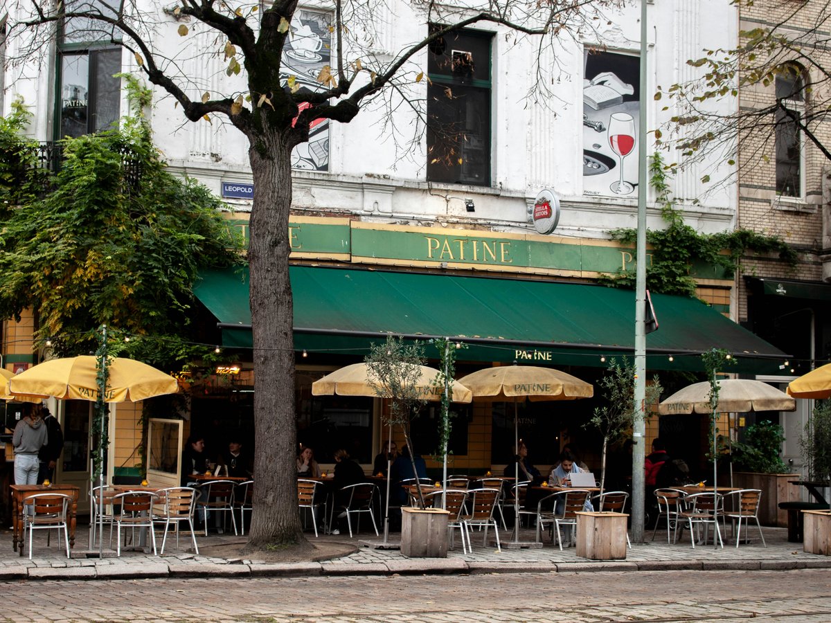 a group of people sitting at tables under umbrellas