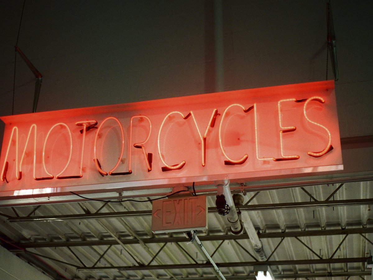 a neon sign that reads motorcycles hanging from a ceiling