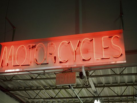 a neon sign that reads motorcycles hanging from a ceiling
