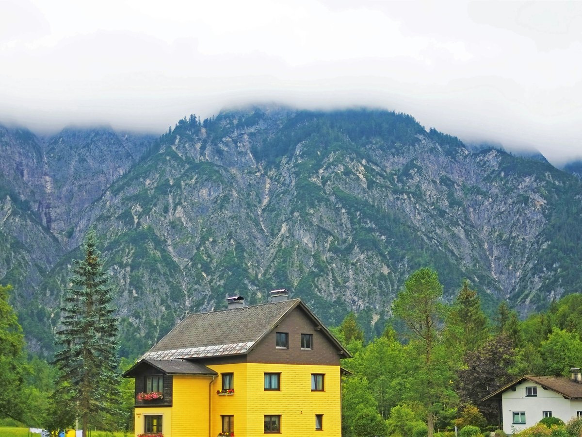 a yellow house with a mountain in the background