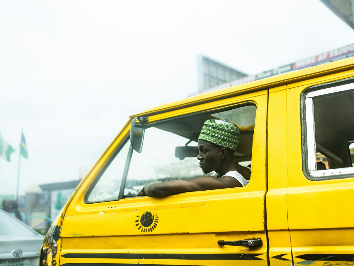 a man driving a yellow van down a street