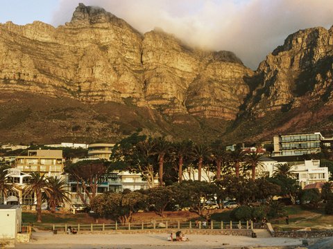 Majestic mountains overlook a coastal town with palm trees.