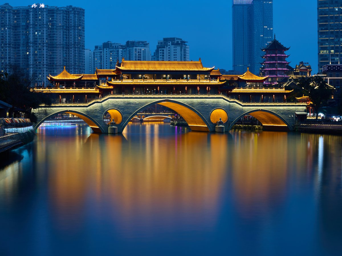 A bridge over a body of water with buildings in the background