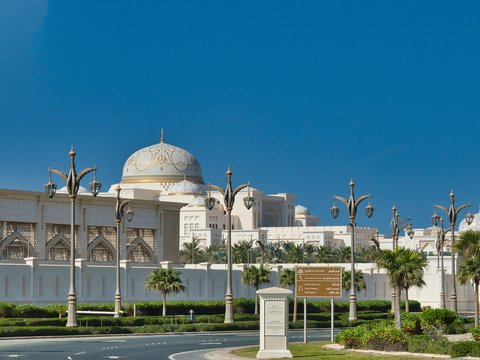 Grand building with dome and palm trees under blue sky