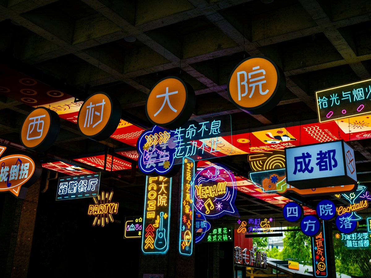 Bright neon signs illuminate a dark street at night