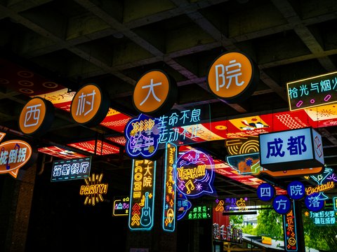 Bright neon signs illuminate a dark street at night