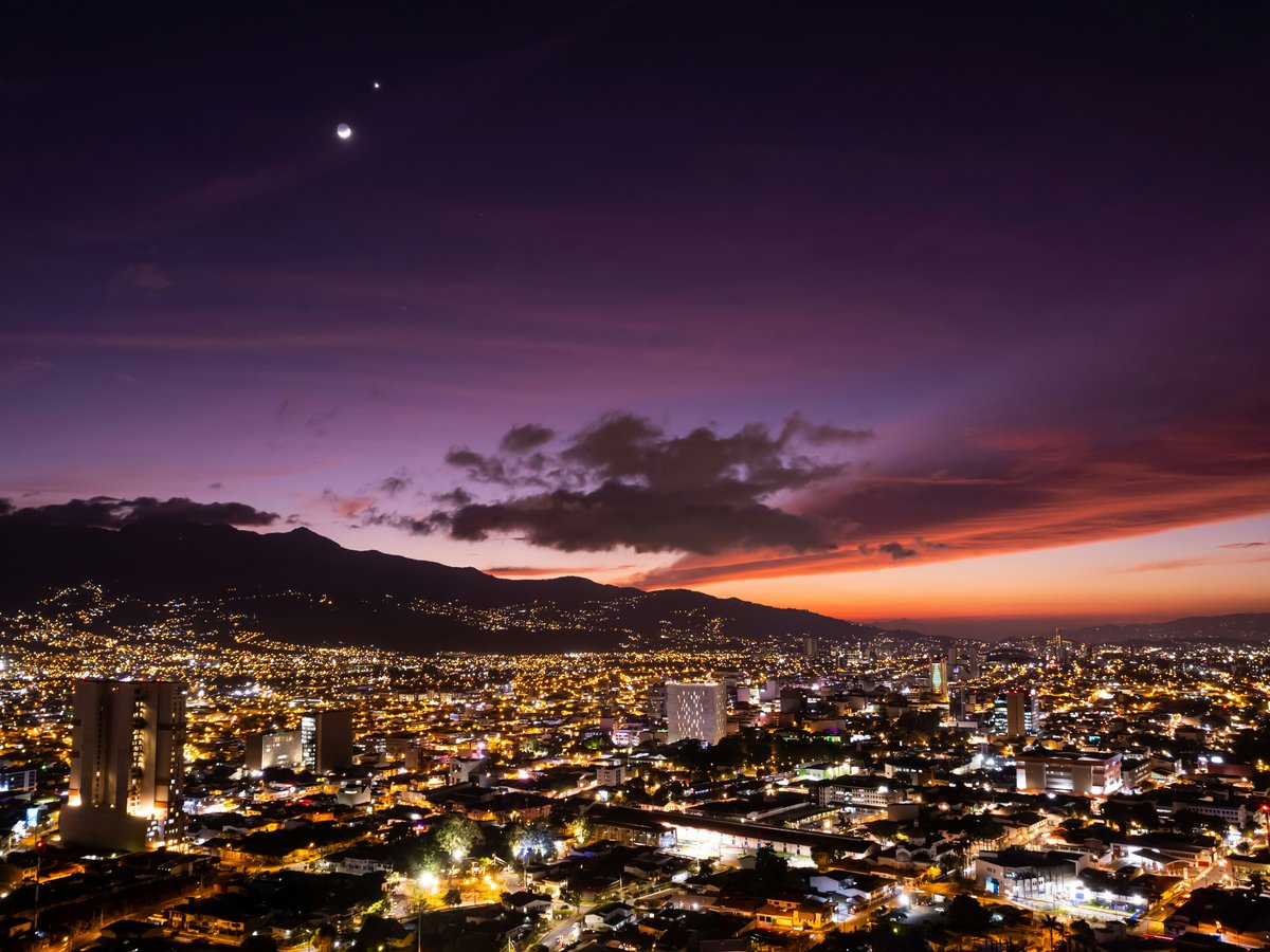 a view of a city at night with the moon in the sky