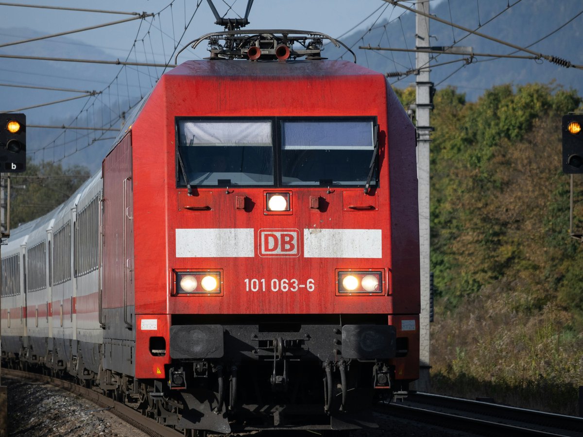 a red train traveling down train tracks next to a forest