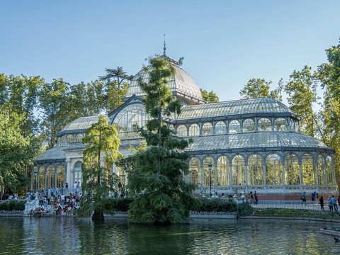 a large glass house surrounded by trees and water