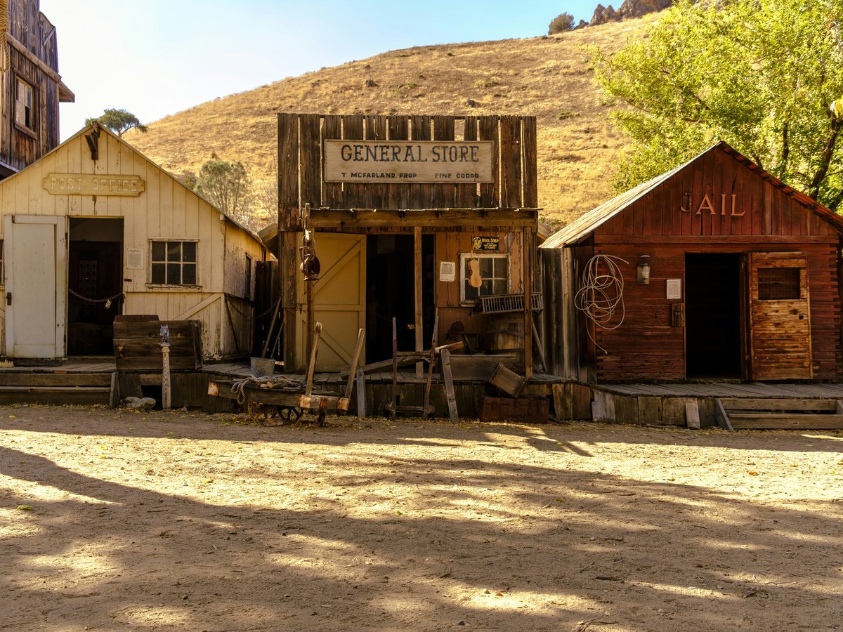 Old western town with three wooden buildings.