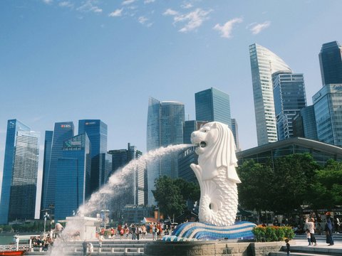 A statue of a dog spewing water in front of a city skyline