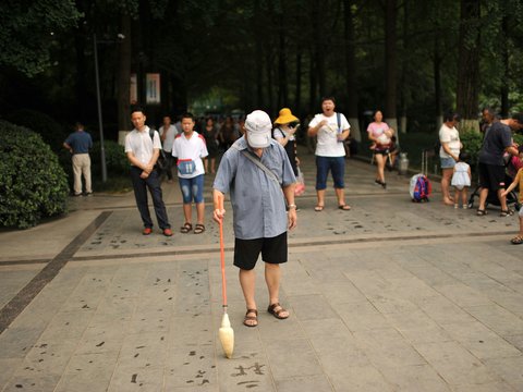 Elderly man playing with a spinning top outdoors